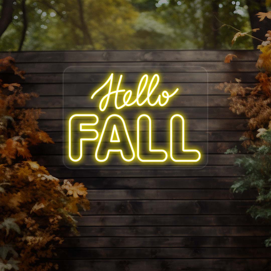 Hello Fall neon sign in yellow on dark wood outdoor wall with autumn leaves