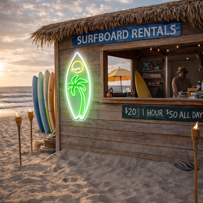 Surfboard-shaped neon sign with palm tree and sunset glowing on a beach surfboard rental shack at sunset.