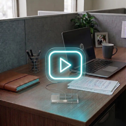 Ice Blue Youtube neon sign on a modern office desk beside a laptop, notebook, and workspace essentials in a professional cubicle setting.