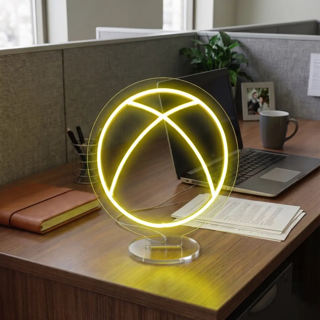 Yellow Xbox neon lamp on a modern office desk beside a laptop, notebook, and workspace essentials in a professional cubicle setting.