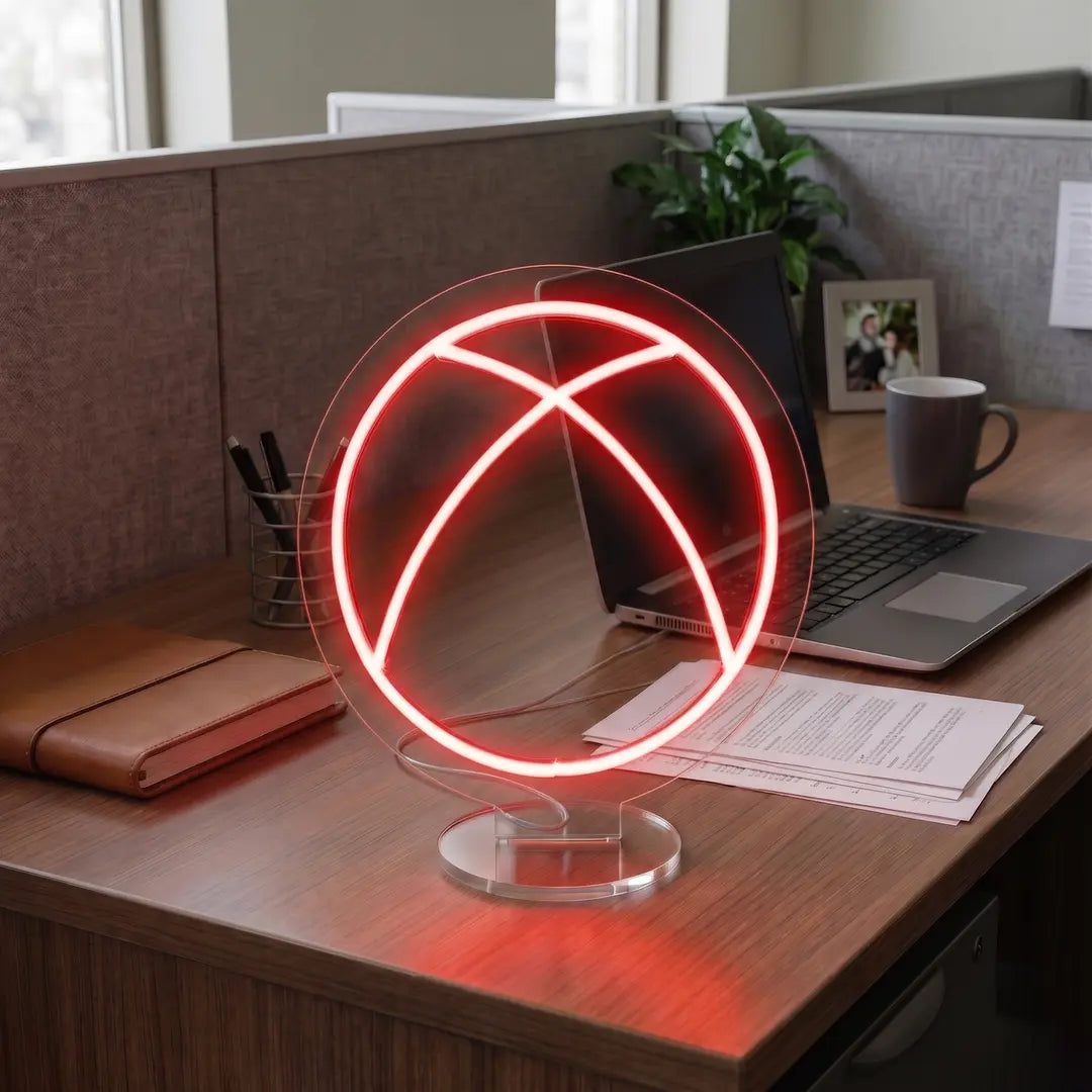 Red Xbox neon lamp on a modern office desk beside a laptop, notebook, and workspace essentials in a professional cubicle setting.