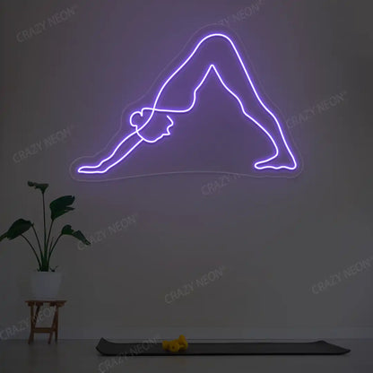 Adho Mukha Svanasana Yoga Neon Sign lighting up in purple color in a yoga room