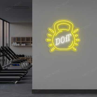 yellow and white do it kettlebell gym neon sign mounted on a wall