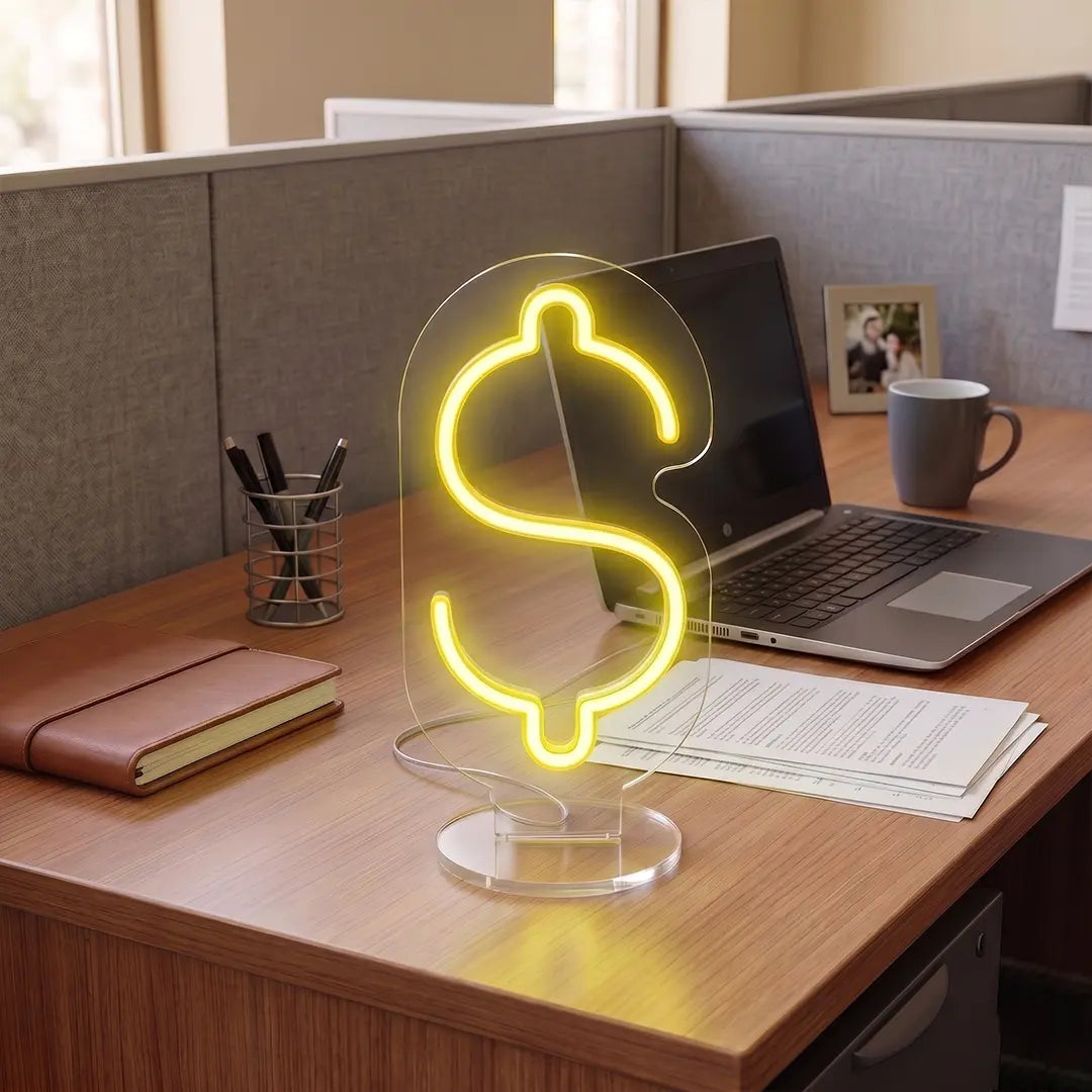 Yellow Color Dollar sign neon lamp glowing on a modern office desk beside a laptop, notebook, and workspace essentials in a professional office setting.