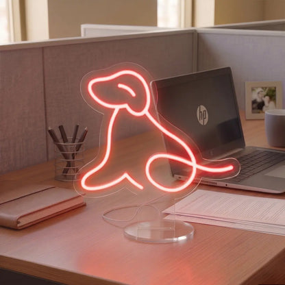 Red Dog Neon lamp on a modern office desk beside a laptop, notebook, and coffee mug, creating a warm and creative workspace atmosphere.