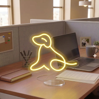 Yellow Dog Neon lamp on a modern office desk beside a laptop, notebook, and coffee mug, creating a warm and creative workspace atmosphere.
