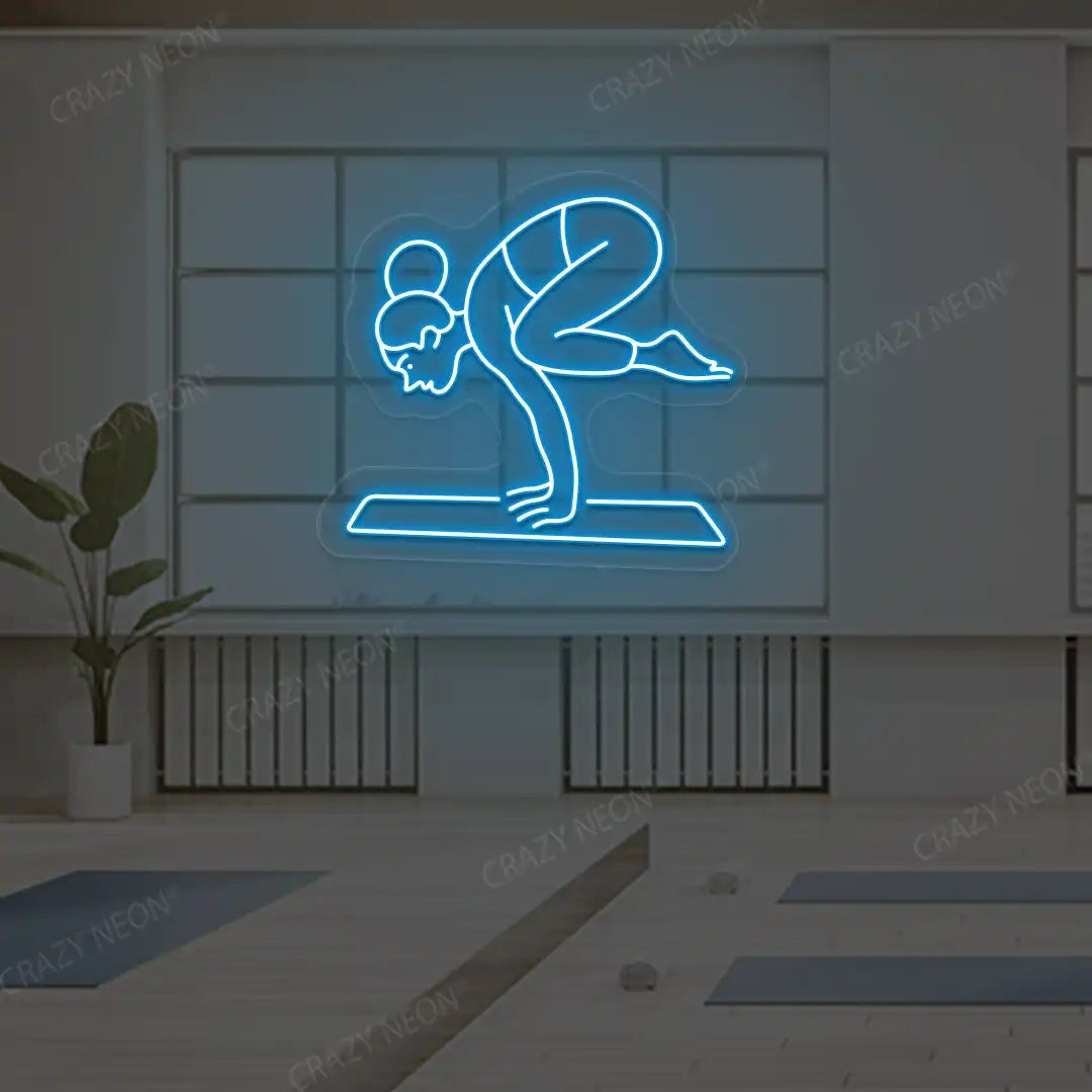 Bakasana Yoga Neon Sign lighting up in ice blue color in a yoga room