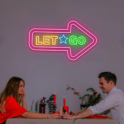 pink let go arrow vintage neon sign mounted on a wall