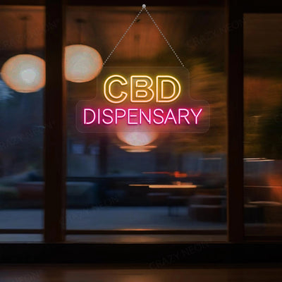 A glowing neon sign reads CBD DISPENSARY with CBD in yellow and DISPENSARY in pink hanging against a large window