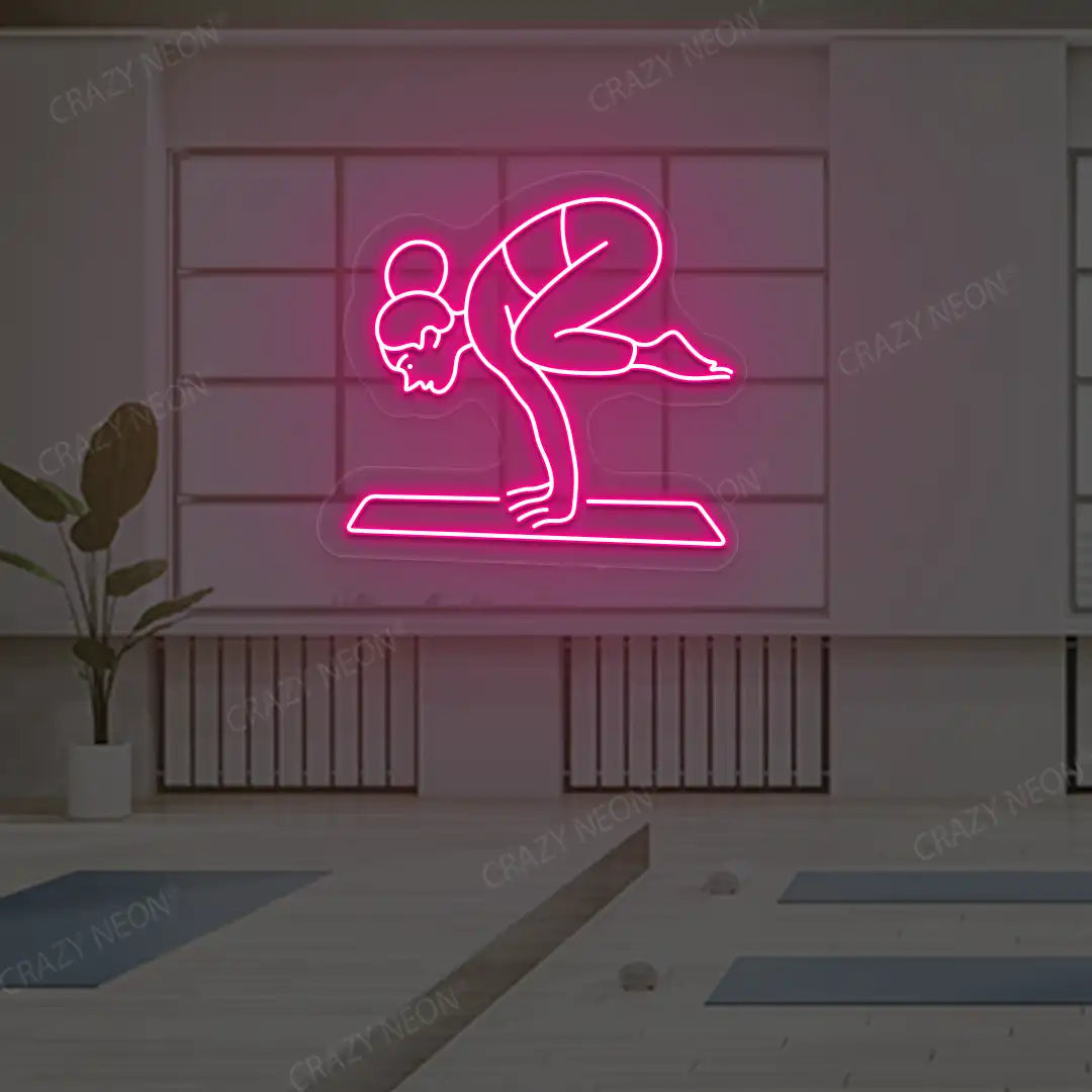 Bakasana Yoga Neon Sign lighting up in pink color in a yoga room