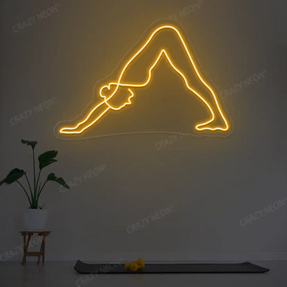 Adho Mukha Svanasana Yoga Neon Sign lighting up in orange color in a yoga room
