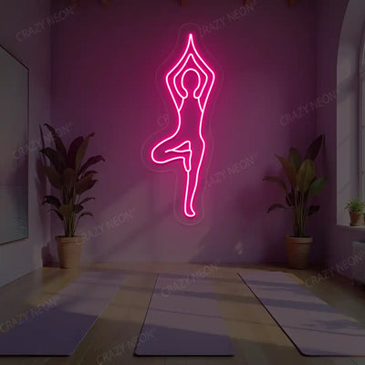 Vrikshasana Yoga Neon Sign lighting up in pink color in a yoga room