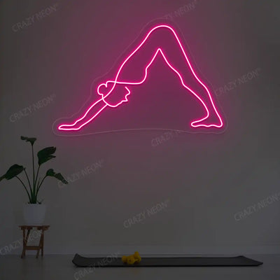 Adho Mukha Svanasana Yoga Neon Sign lighting up in pink color in a yoga room