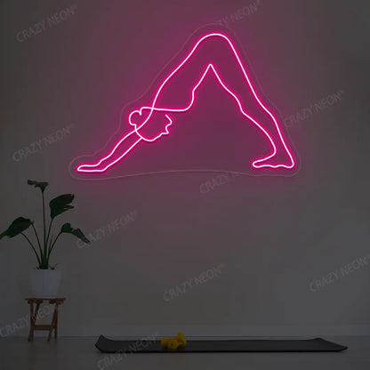 Adho Mukha Svanasana Yoga Neon Sign lighting up in pink color in a yoga room