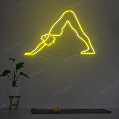 Adho Mukha Svanasana Yoga Neon Sign lighting up in yellow color in a yoga room