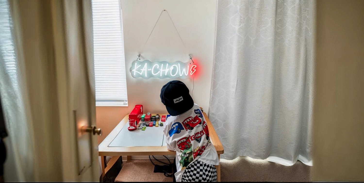 Child playing at desk with Kachow neon sign and toy cars in bright kids room