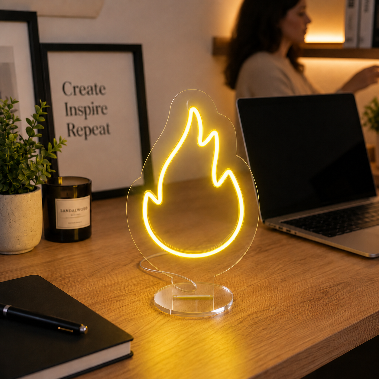 Flame Neon Desk Lamp glowing in warm yellow light on a wooden desk beside a laptop, adding a creative and inspiring touch to a modern workspace.
