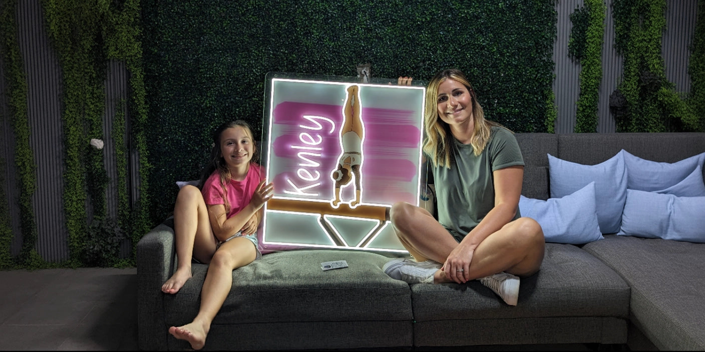 Custom Kenley gymnast neon sign held by girl and woman on modern gray sofa with green wall decor