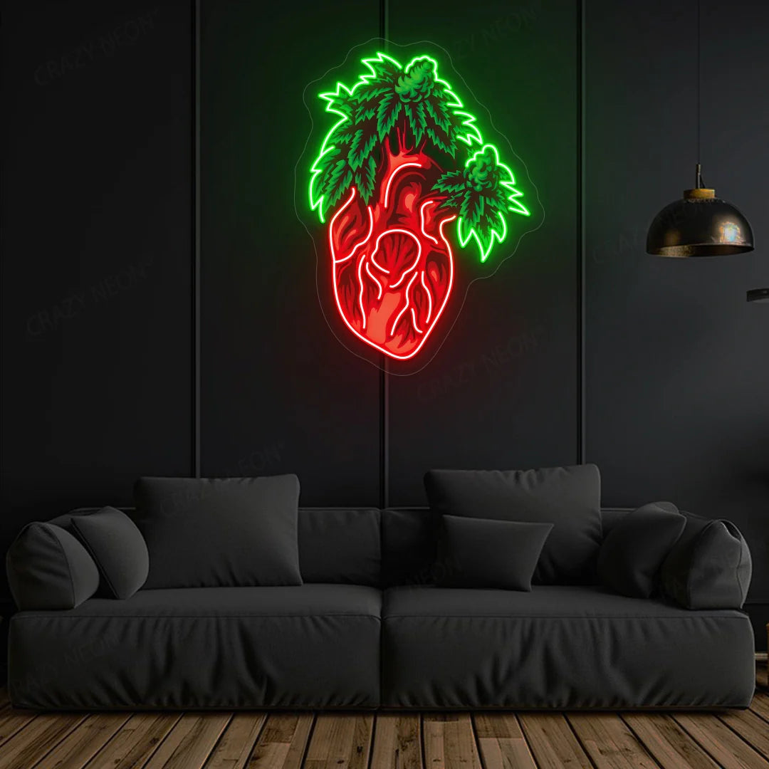 Neon wall art featuring a glowing anatomical heart with bright red tubing and luminous green leaves sprouting from the top displayed on a dark wall