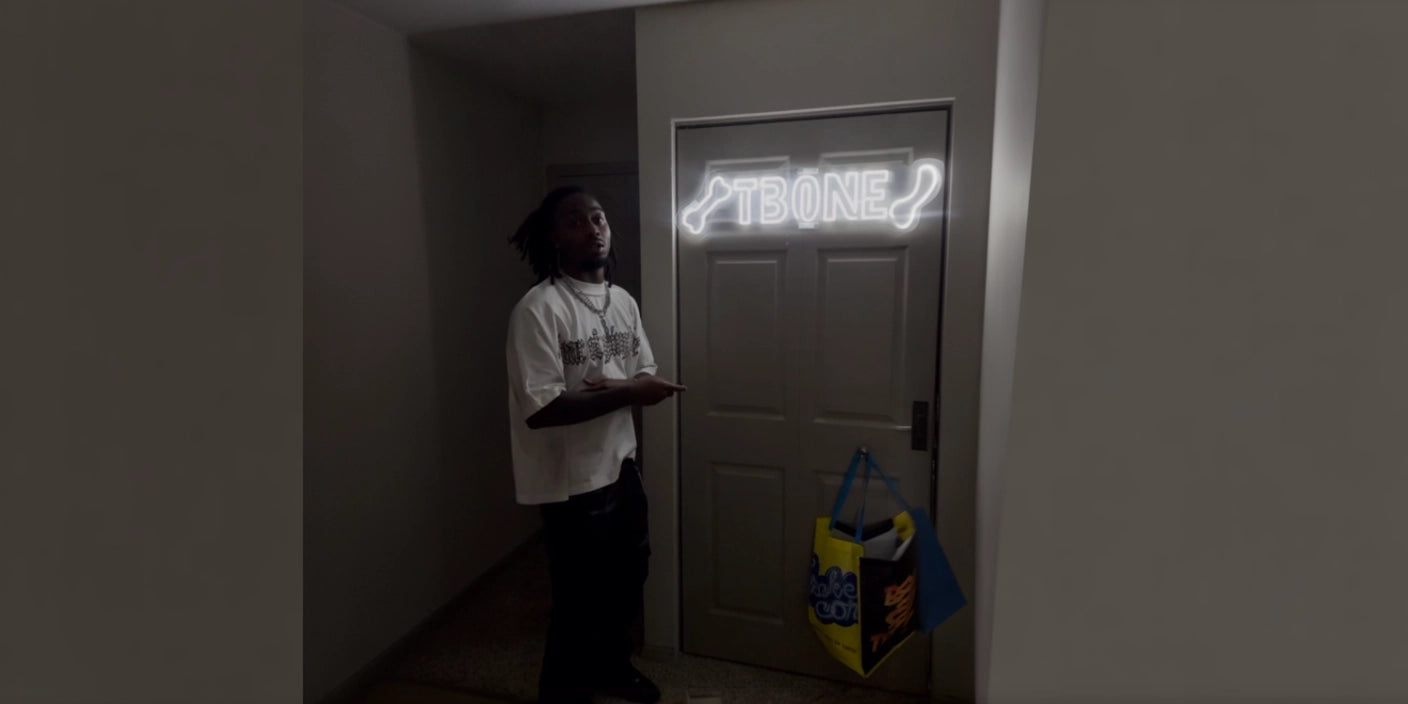 Man posing beside TBONE custom pet neon sign in white above interior door 