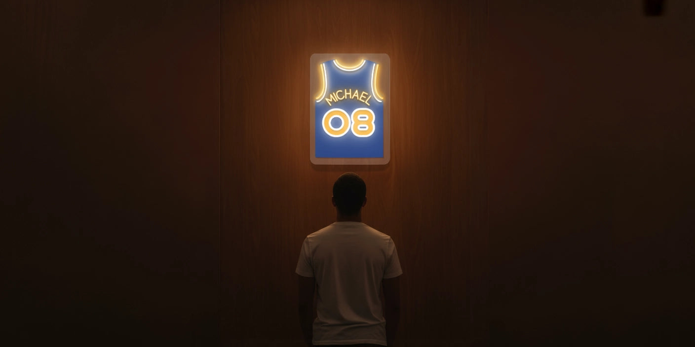 Person in white tshirt standing in front of illuminated blue Michael 08 basketball jersey neon artwork sign on wood wall in dark room