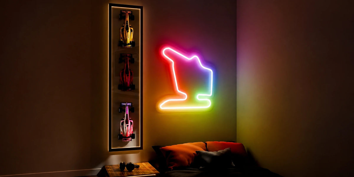 Grand Prix Circuit Neon Sign mounted on a dark wall beside a display case of miniature race cars