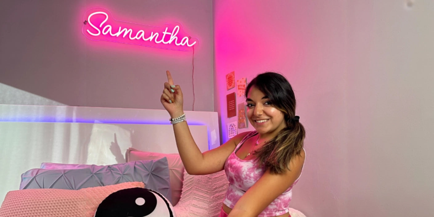Teen girl in pink bedroom pointing at custom Samantha neon sign wall decor 