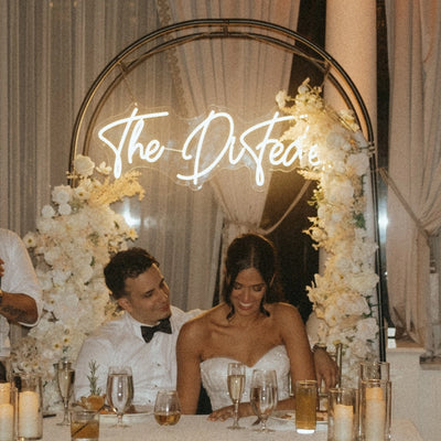 Bride and groom at sweetheart table under The DiFeas custom white neon sign